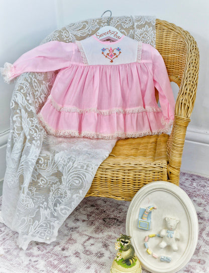 6-9 months. Pink Miniworld  deess with white embroidered bib