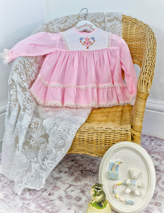 6-9 months. Pink Miniworld  deess with white embroidered bib