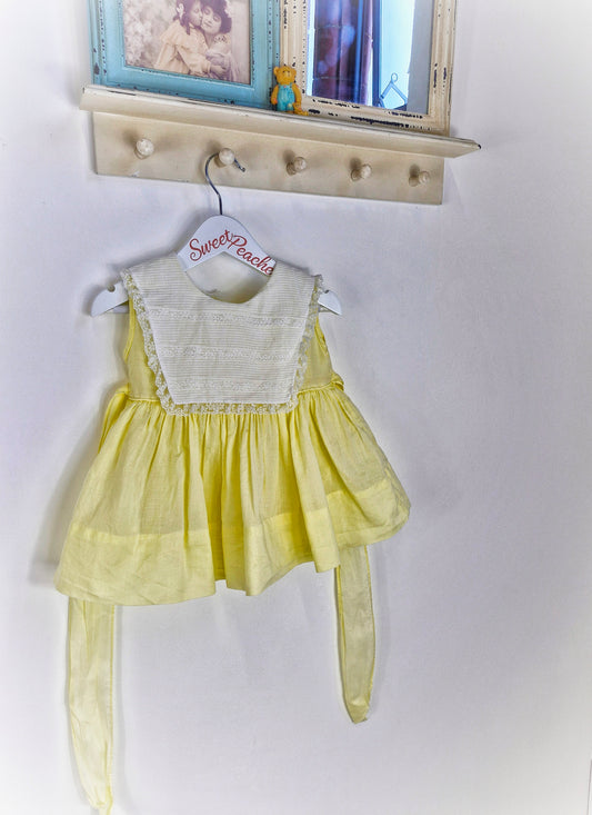 12-18 months. Lemon sleeveless dress with white bib