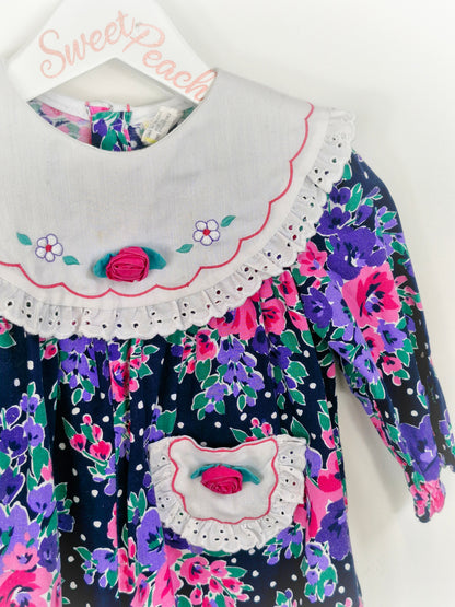 Best fit 18 months. Floral romper with embroidered white bib and pocket
