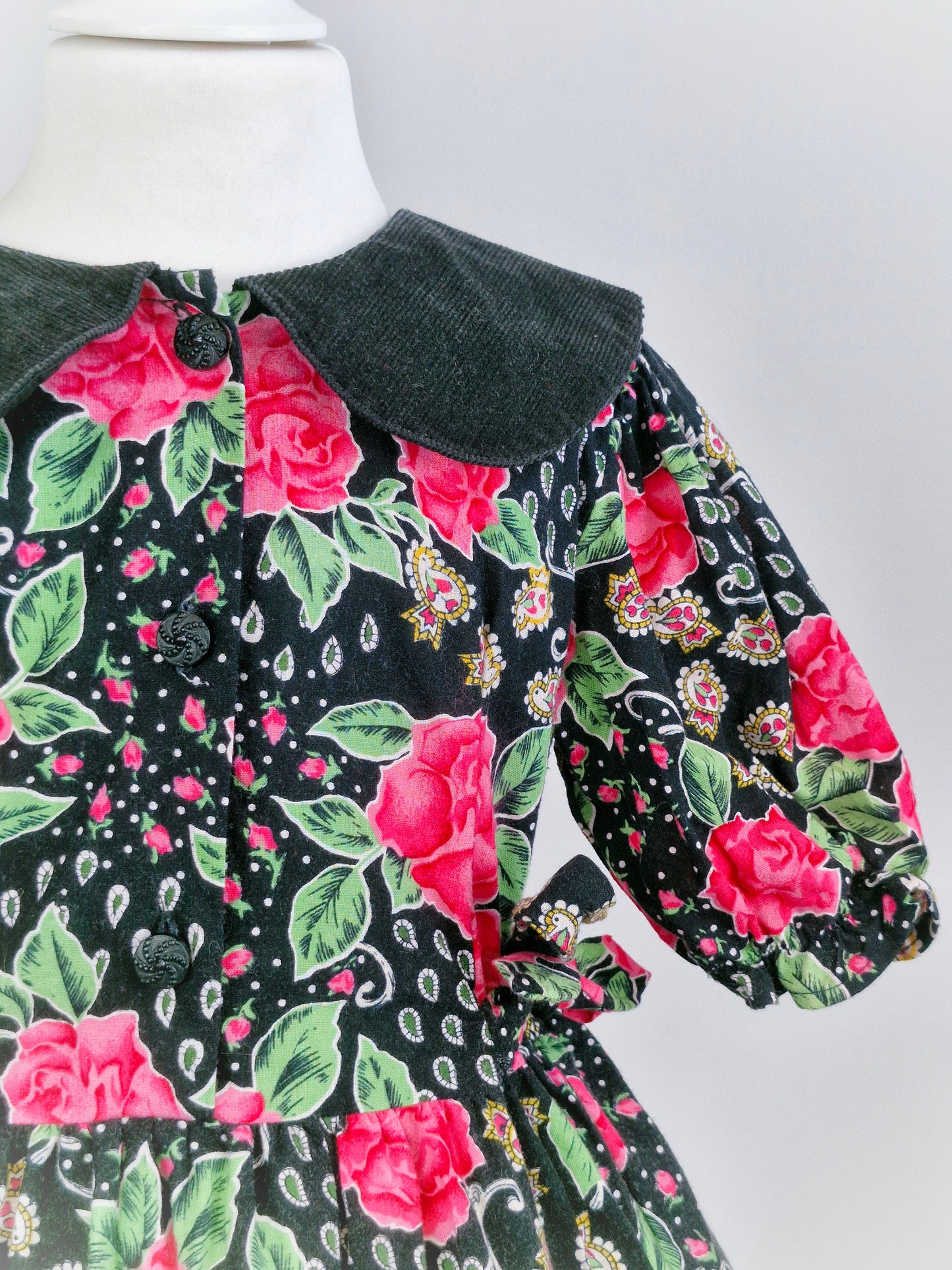 5-6 years. Black dress with pink roses, paisley patterns and a corduroy collar.