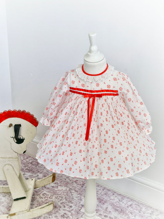 2 years. White dress with mini pleats, red details and ribbon and white lace collar.