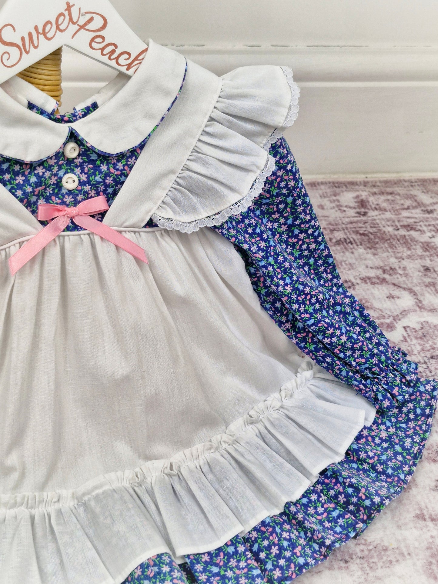 12-18 months. Navy long sleeve dress with floral print and white, mock pinny. New York Kids.