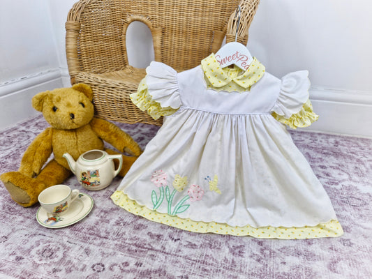 12-18 months. Samara. Lemon floral dress with white embroidered pinny with flutter sleeves