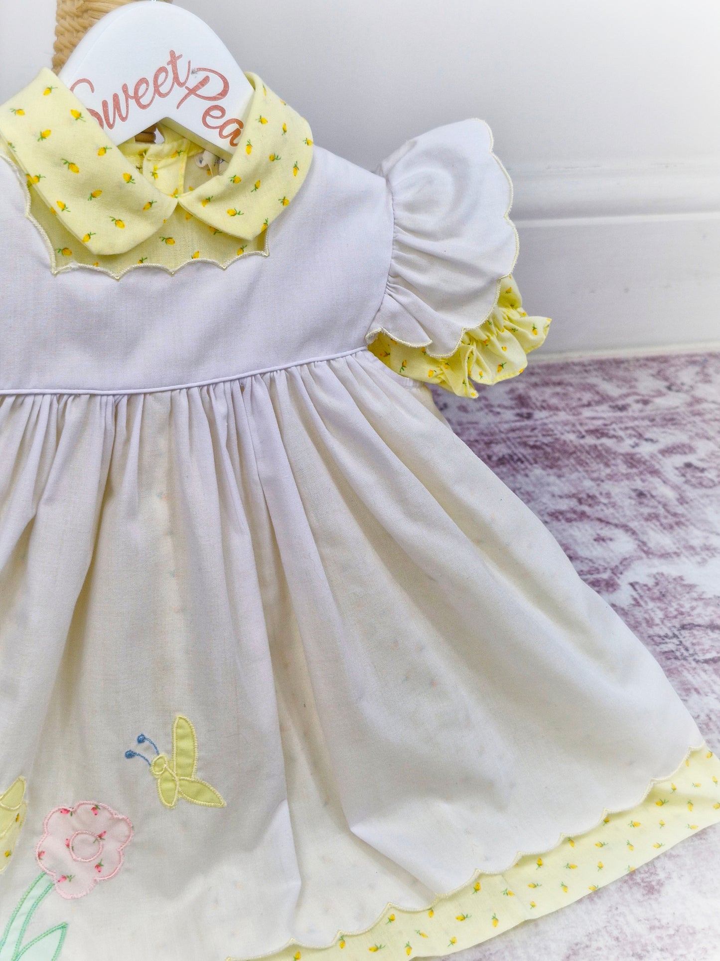 12-18 months. Samara. Lemon floral dress with white embroidered pinny with flutter sleeves