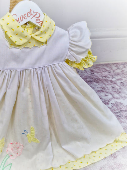 12-18 months. Samara. Lemon floral dress with white embroidered pinny with flutter sleeves