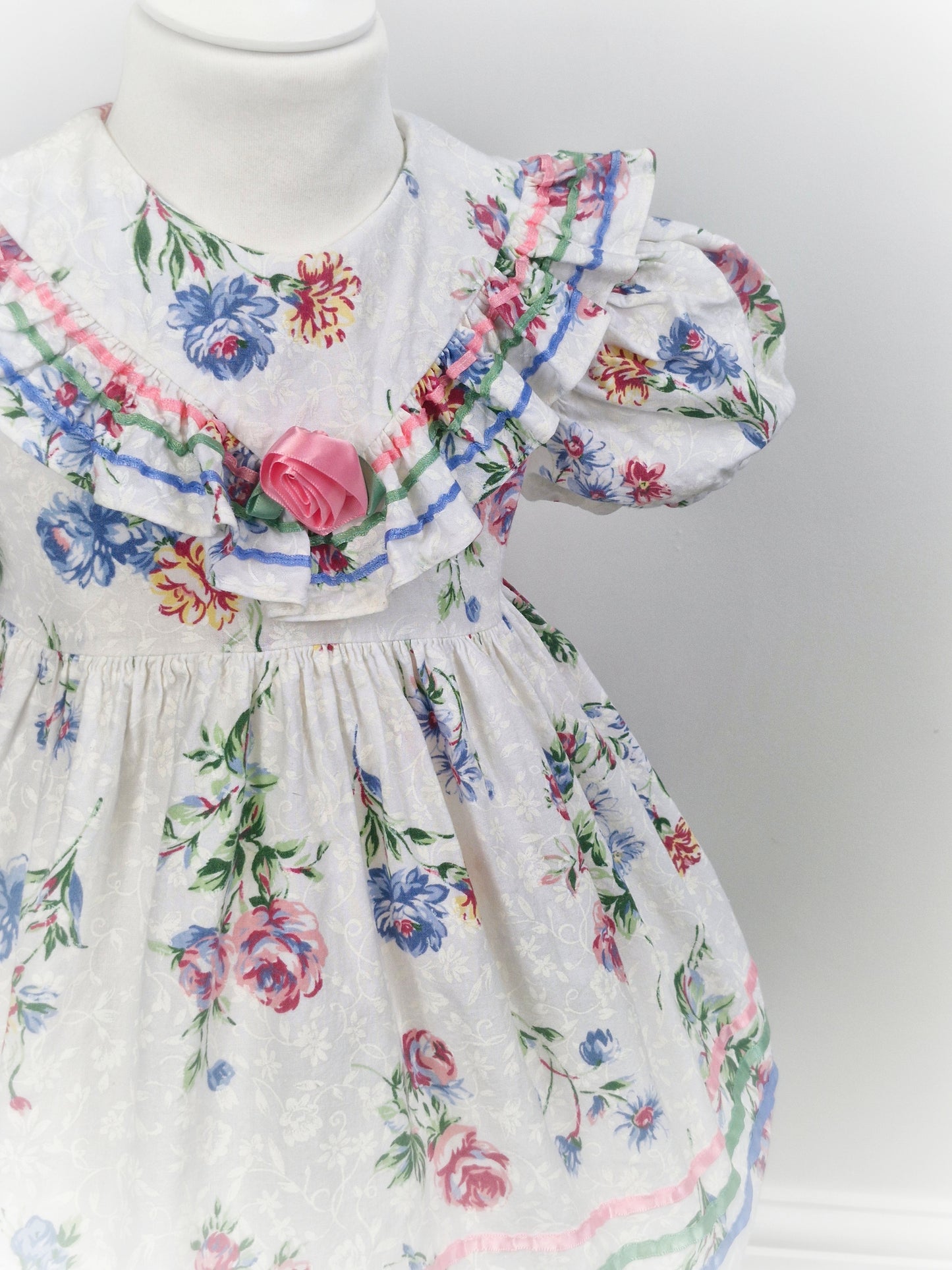 3 years. White dress with floral print, ribbon and rose on ruffled bib