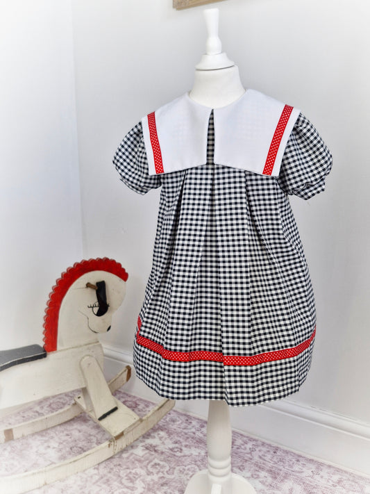 5-6 years. Black and white gingham dress with red ribbon trim and white bib
