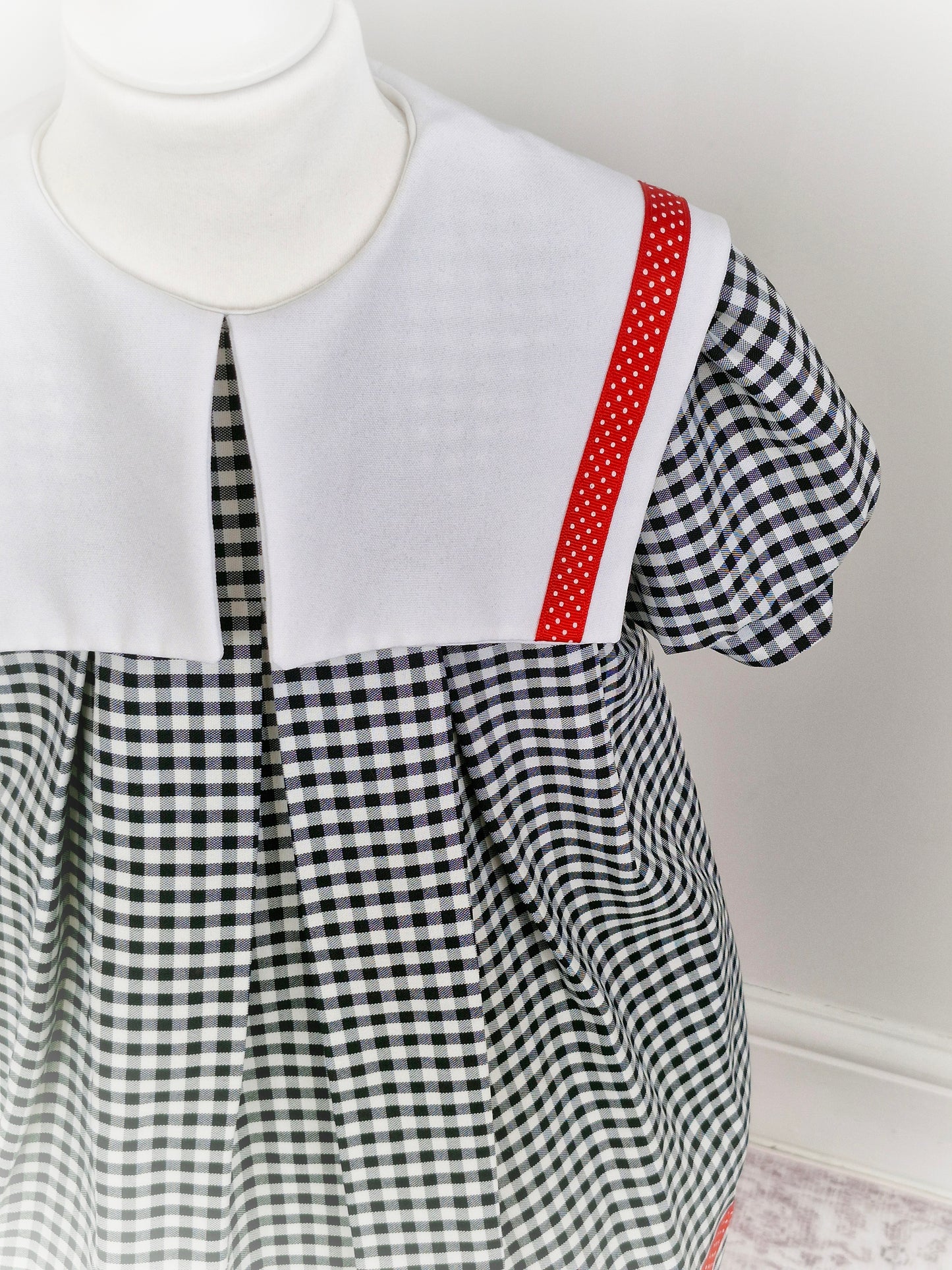 5-6 years. Black and white gingham dress with red ribbon trim and white bib