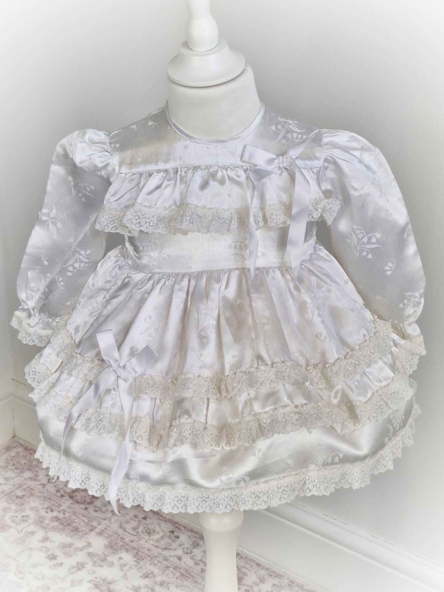 12-18 months. White satin dress with puffed sleeves, ribbon and lace