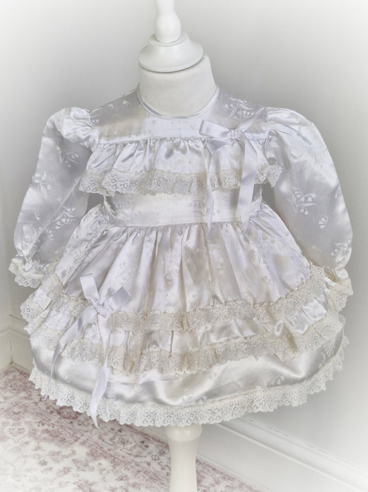 12-18 months. White satin dress with puffed sleeves, ribbon and lace