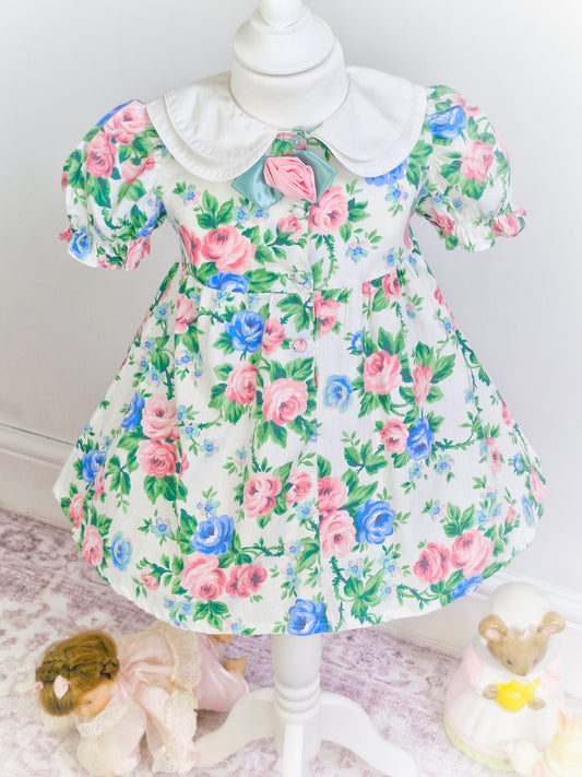 3 years. Blue and pink floral dress with double white collar and rose centre