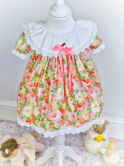 2-3 years. Floral vintage dress with white bib, pink ribbon, and rosette