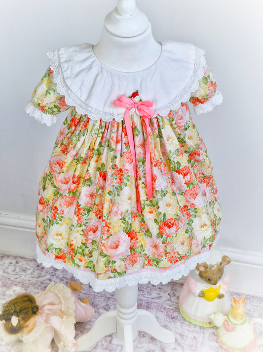 2-3 years. Floral vintage dress with white bib, pink ribbon, and rosette