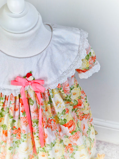2-3 years. Floral vintage dress with white bib, pink ribbon, and rosette