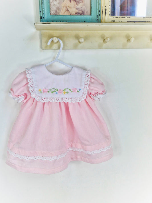 12-18 months. Pink dress with white bib, embroidered with flowers