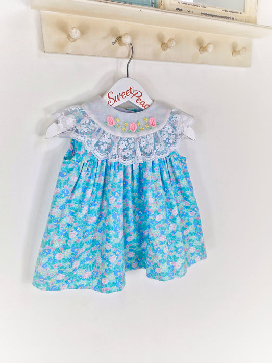 12 months. Blue floral sleeveless Alyssa vintage dress with embroidered flowers and lace on bib