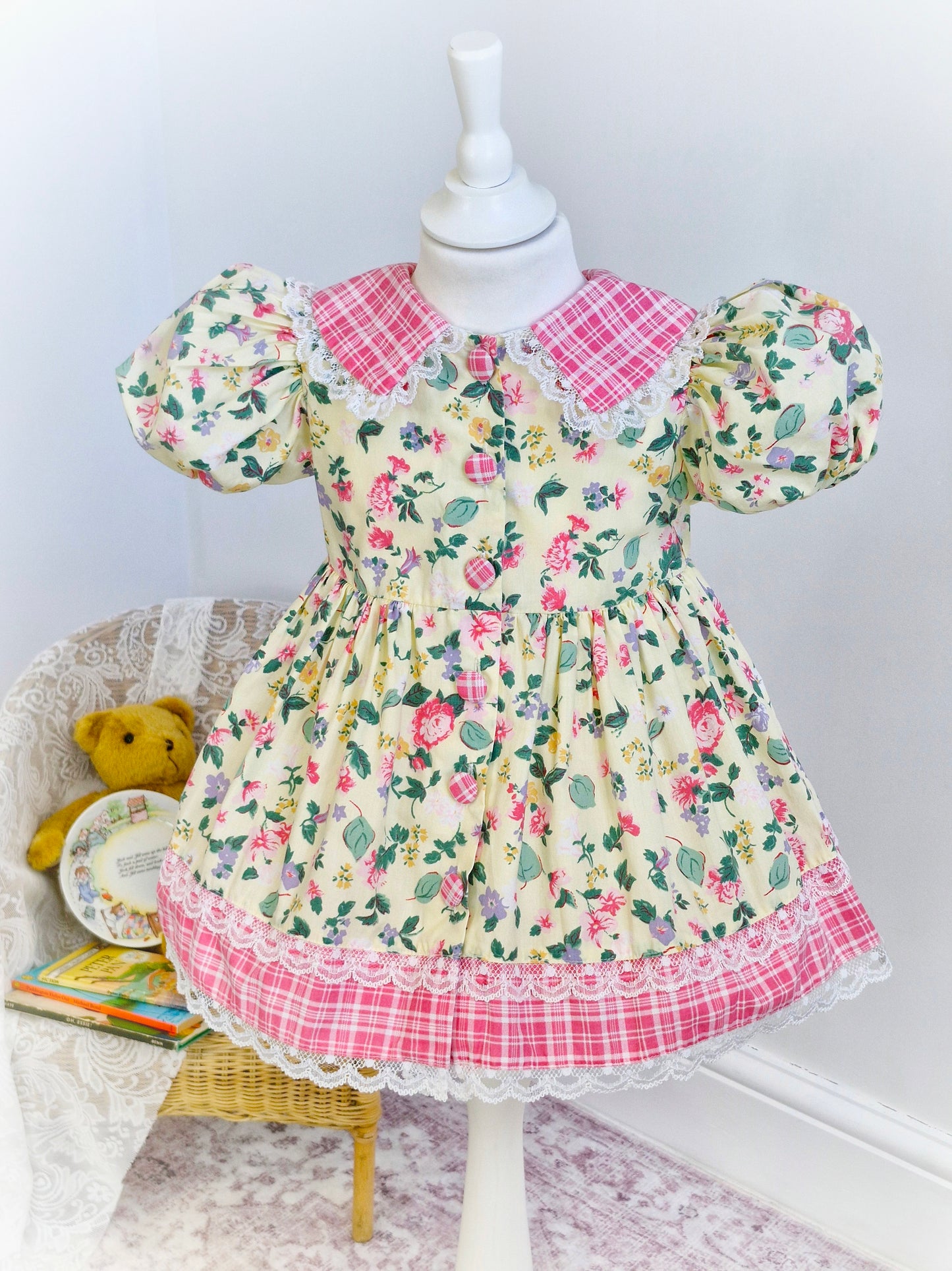 2-3 years. Pale lemon vintage dress by Little Precious with leaf and flower print, pink and white checked collar, hem and buttons. Lace trim