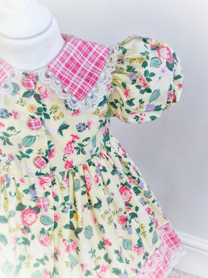 2-3 years. Pale lemon vintage dress by Little Precious with leaf and flower print, pink and white checked collar, hem and buttons. Lace trim