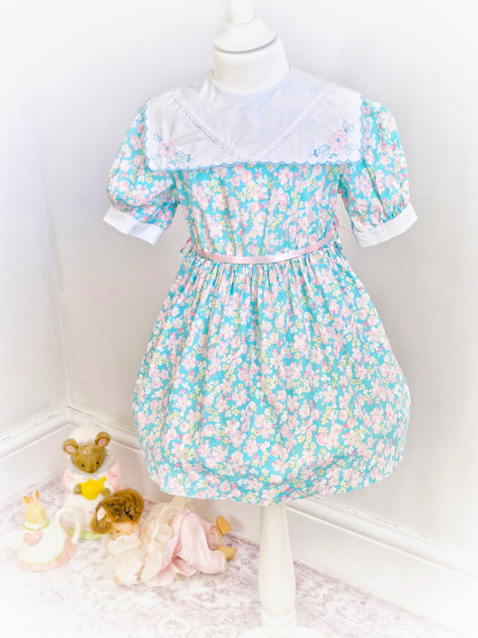 4 years. Blue floral dress with white scalloped edge bib, embroidered with flowers. JC Penney