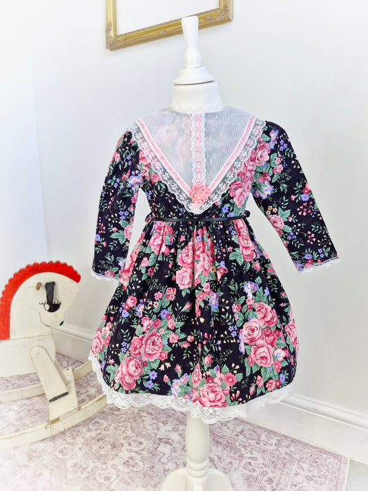 4 years. Black Cuddle Teen vintage dress with pink floral details, white lace bib and pink ribbon
