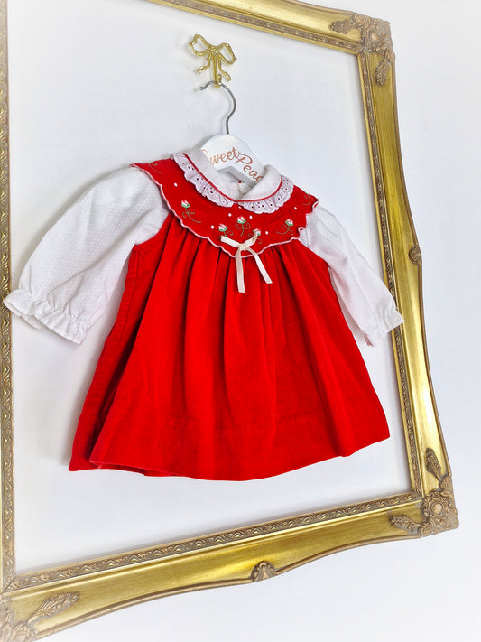 6-9 months. Red velvet dress with white, collared blouse underneath.