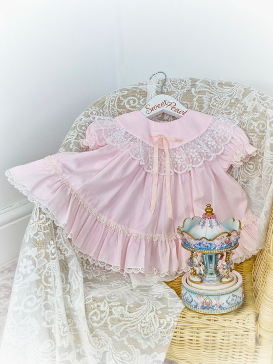 9-12 months. Pink vintage Bryan with lace trim on bib and hem