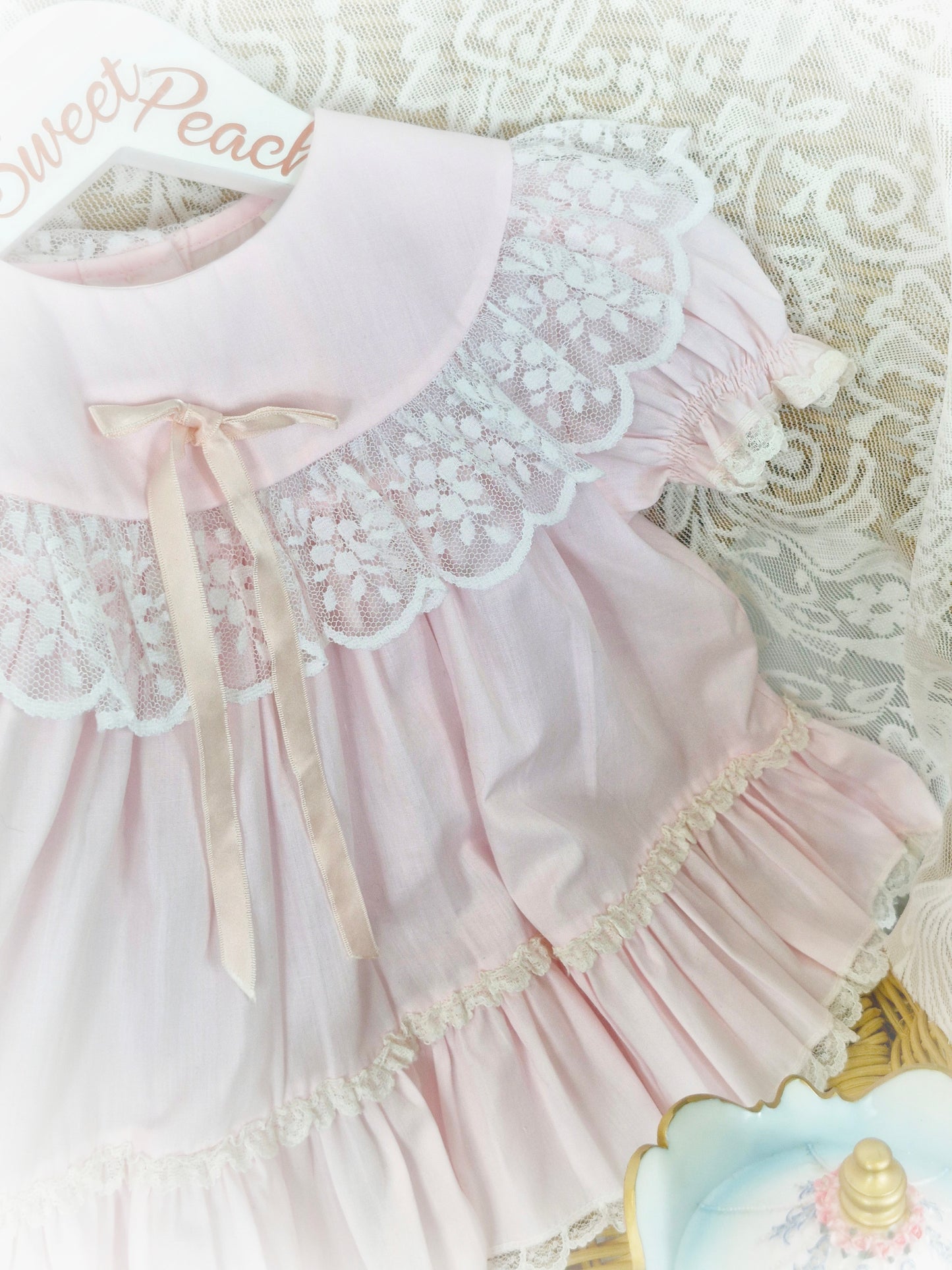 9-12 months. Pink vintage Bryan with lace trim on bib and hem