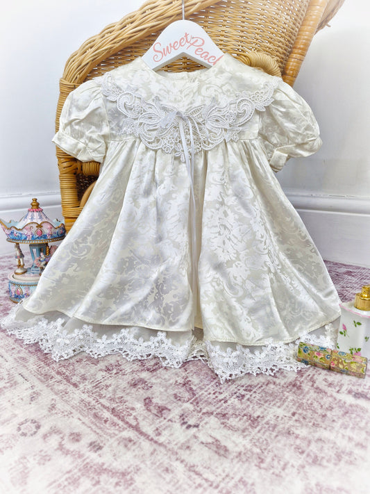 18-24 months. Off-white satin dress with floral patterns and lace details