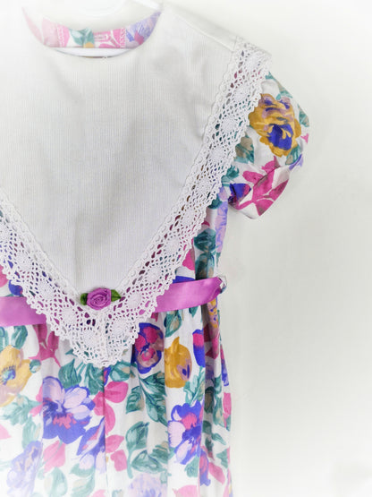 2-3 years. Purple floral romper with large white bib