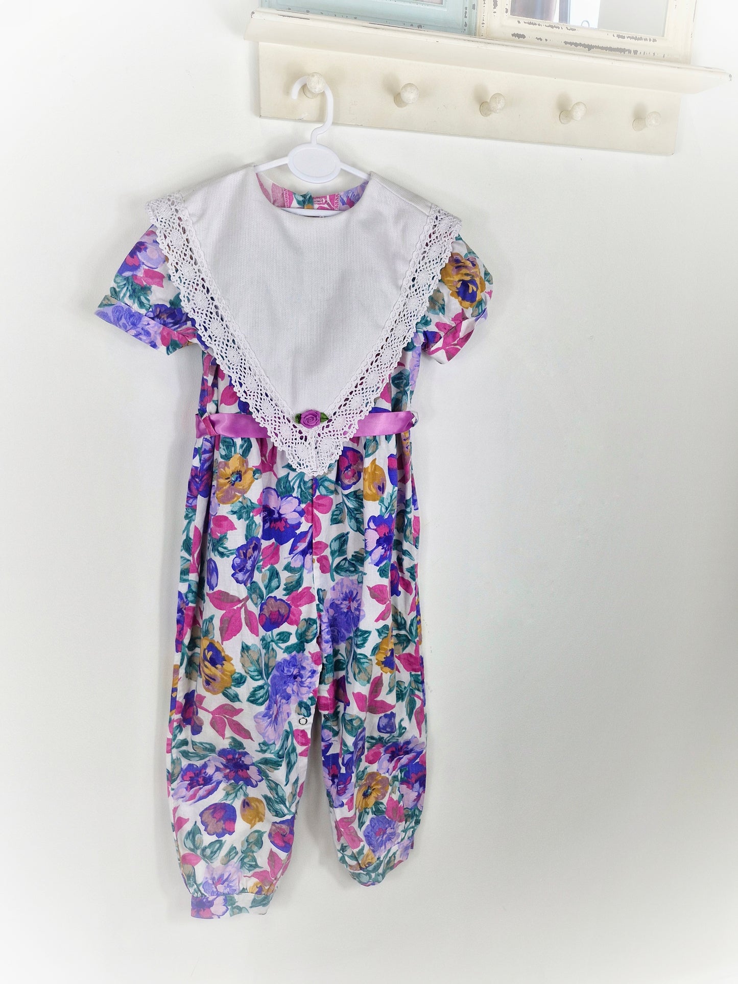 2-3 years. Purple floral romper with large white bib