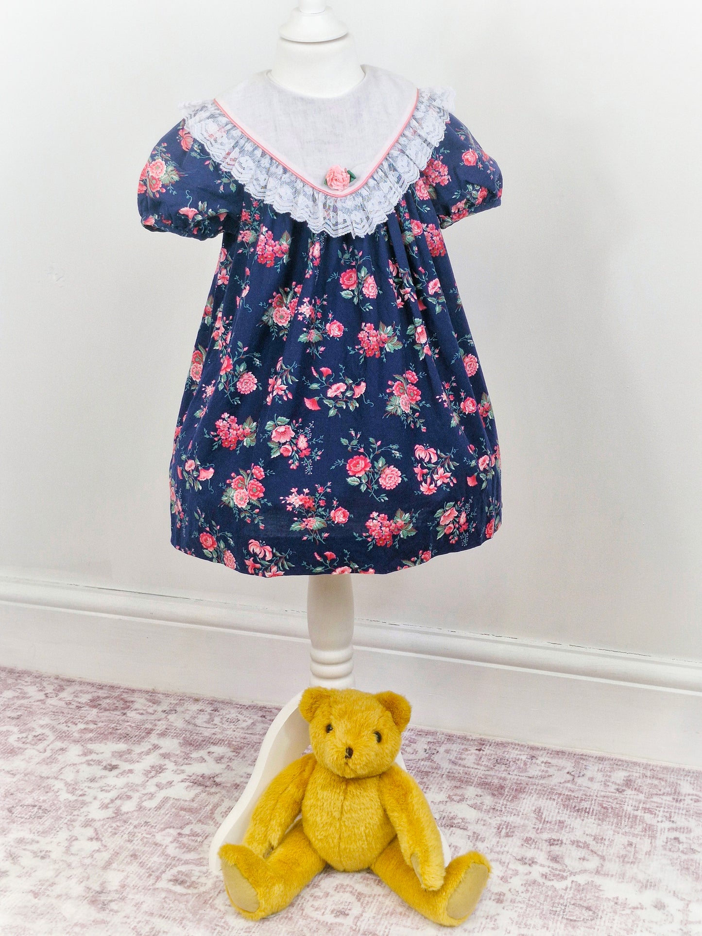 5 years. Navy vintage Rare Editions with pink floral print and large bib with lace hem