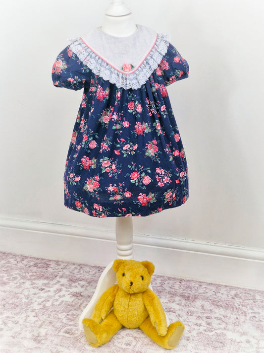 5 years. Navy vintage Rare Editions with pink floral print and large bib with lace hem