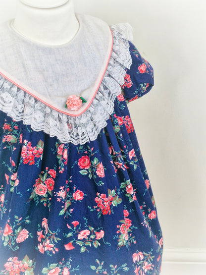 5 years. Navy vintage Rare Editions with pink floral print and large bib with lace hem