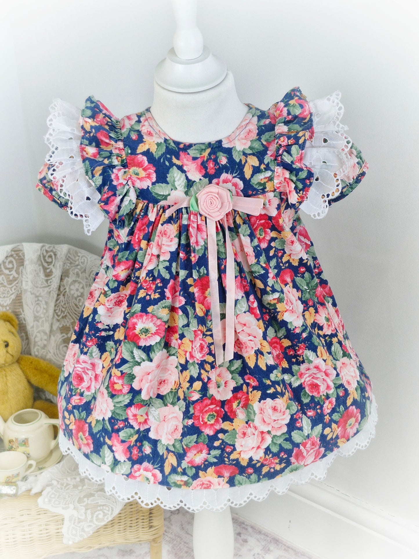 2 years. Navy and pink floral dress with white broderie anglais flutter sleeves and hem from Rare Editions