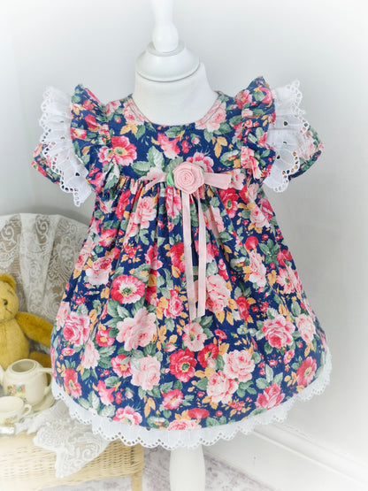 2 years. Navy and pink floral dress with white broderie anglais flutter sleeves and hem from Rare Editions