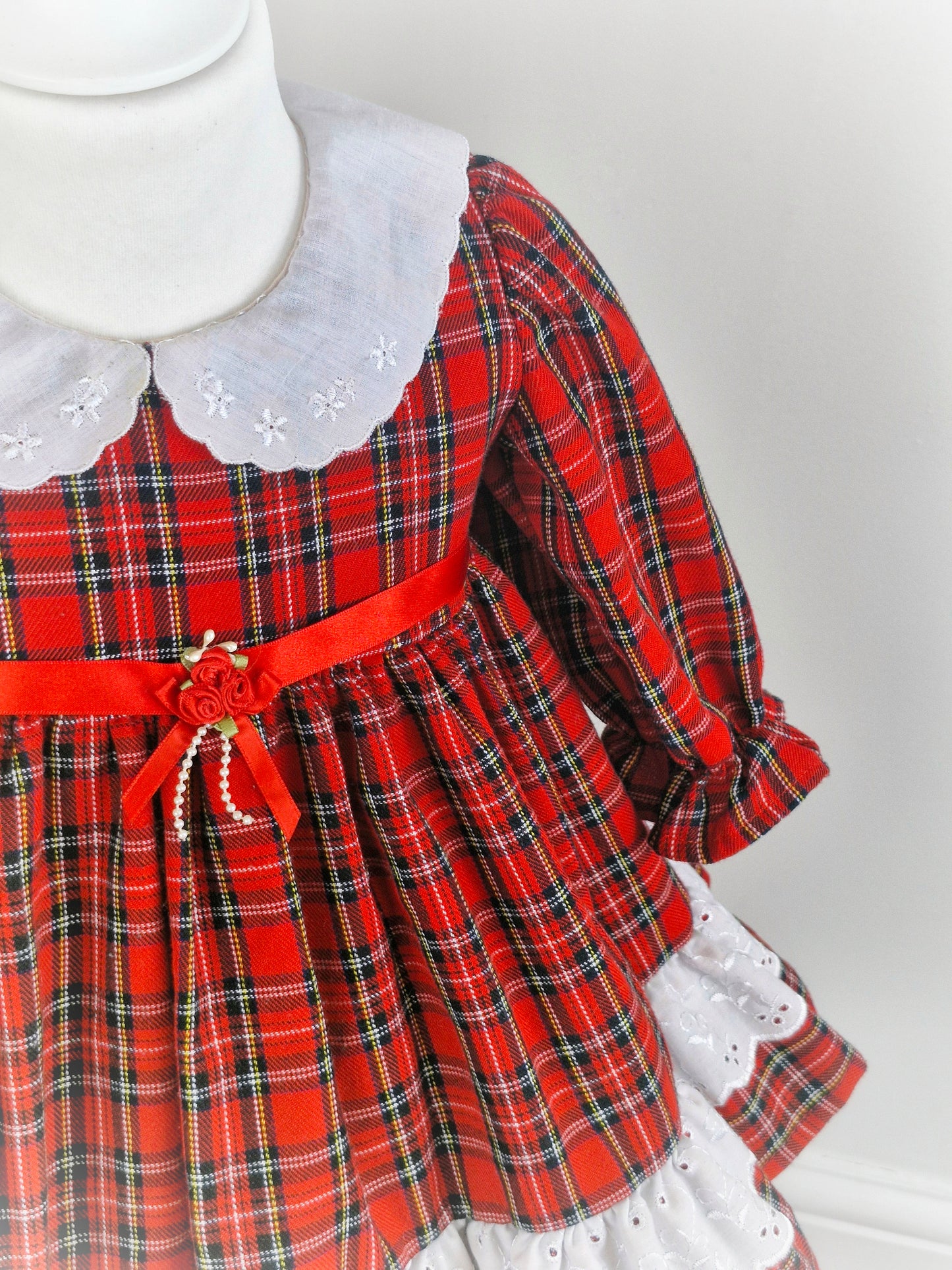 2 years. Red tartan dress with white collar embroidered with dainty flowers. Ribbon belt.
