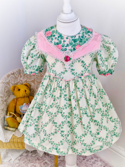 3 years. Vintage Carters dress, cream with green vine leaves, pink roses and double bib