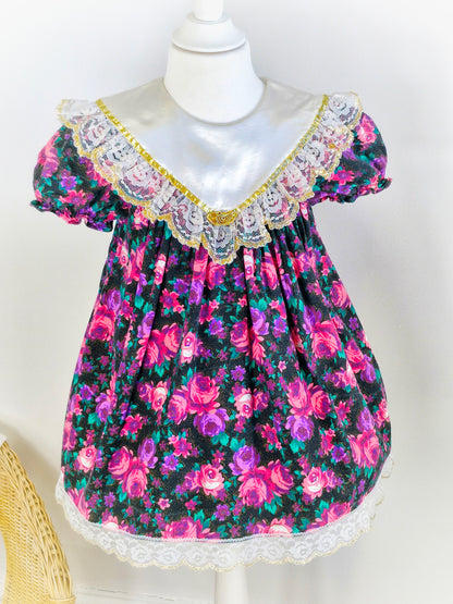 3-4 years. Vintage Jolene, black dress with pink and purple flowers, white satin bib with lace and gold trim