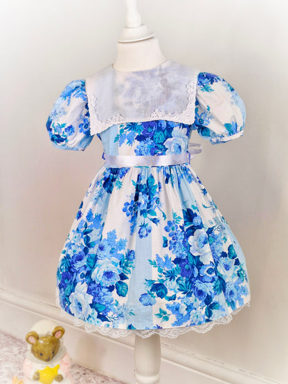 4 years. Good Lad of Philadelphia, white dress with blue floral print, puff sleeves and white bib