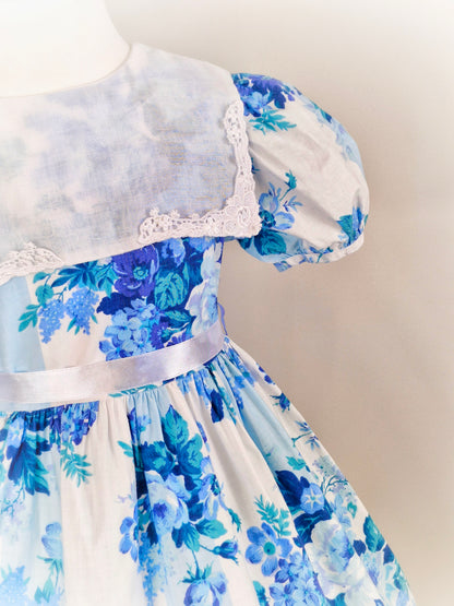 4 years. Good Lad of Philadelphia, white dress with blue floral print, puff sleeves and white bib