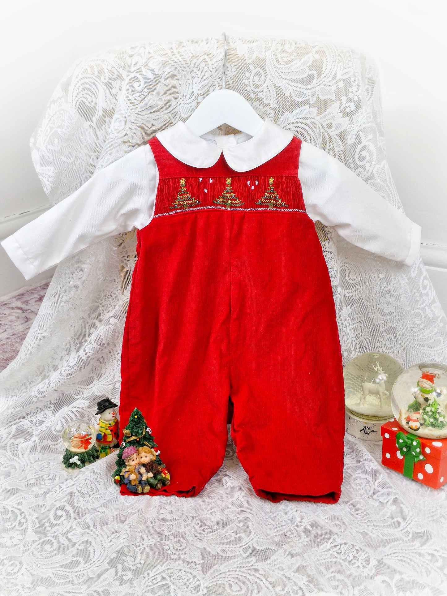 6-9 months. Two-piece set. Red corduroy dungarees with smocking and embroidered Christmas trees. Includes white collared shirt.