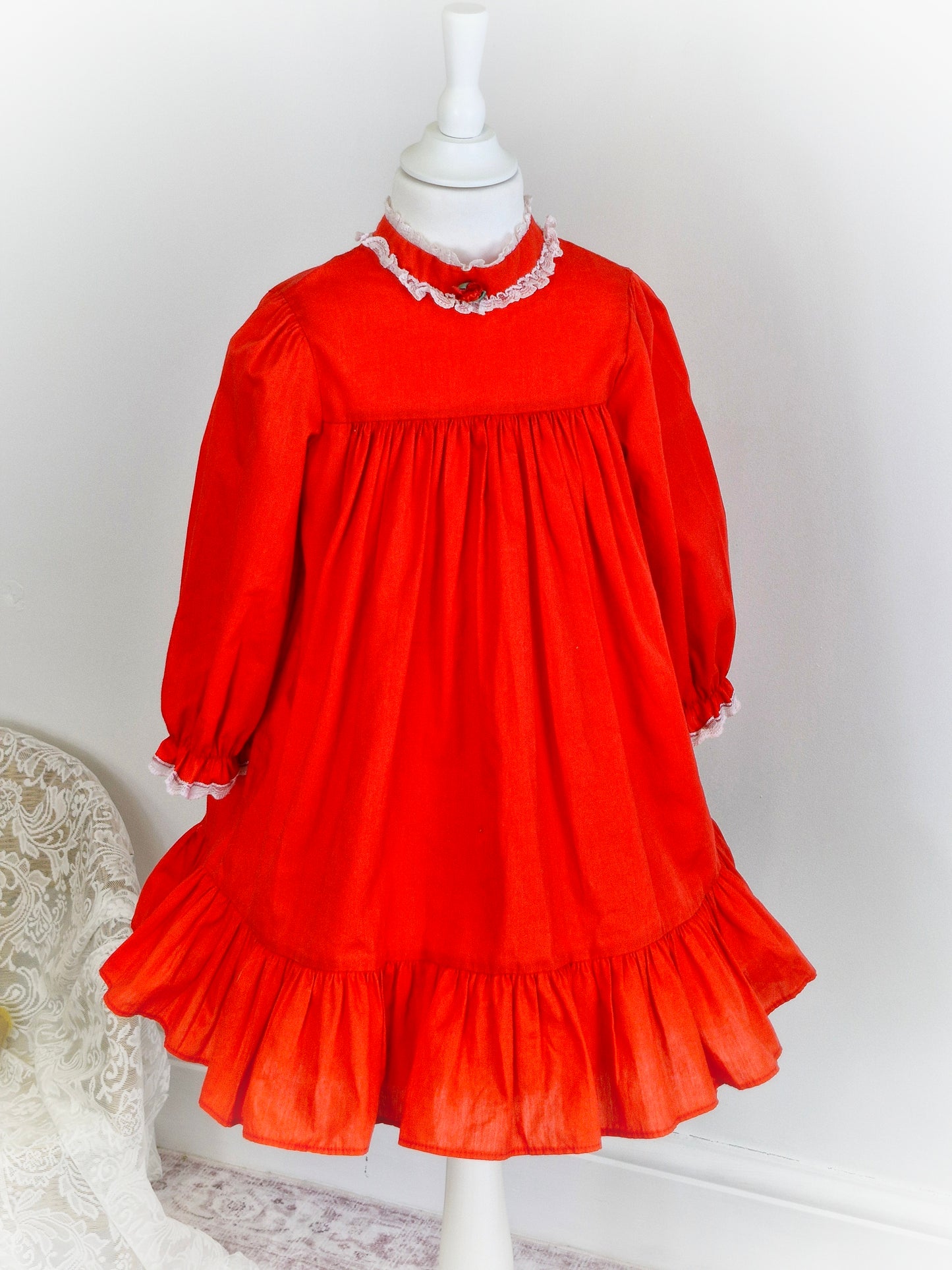 5 years. Red vintage Bryan with high neck and long sleeves. Lace and rosette detailing