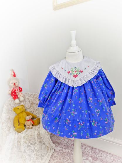 2 years. Blue floral vintage dress with large white broderie anglais bib embroidered with hearts and flowers