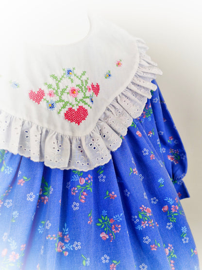 2 years. Blue floral vintage dress with large white broderie anglais bib embroidered with hearts and flowers