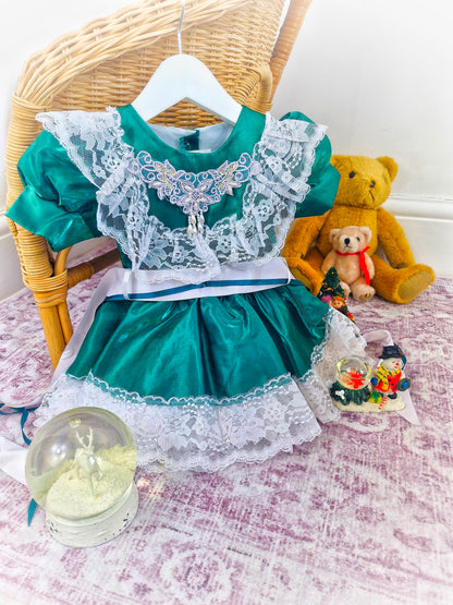12-18 months. Green satin dress with white lace and ribbon