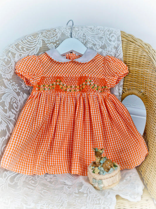 9 months. Vintage inspired smock dress by Carriage Boutique. Orange and white gingham with embroidered flowers