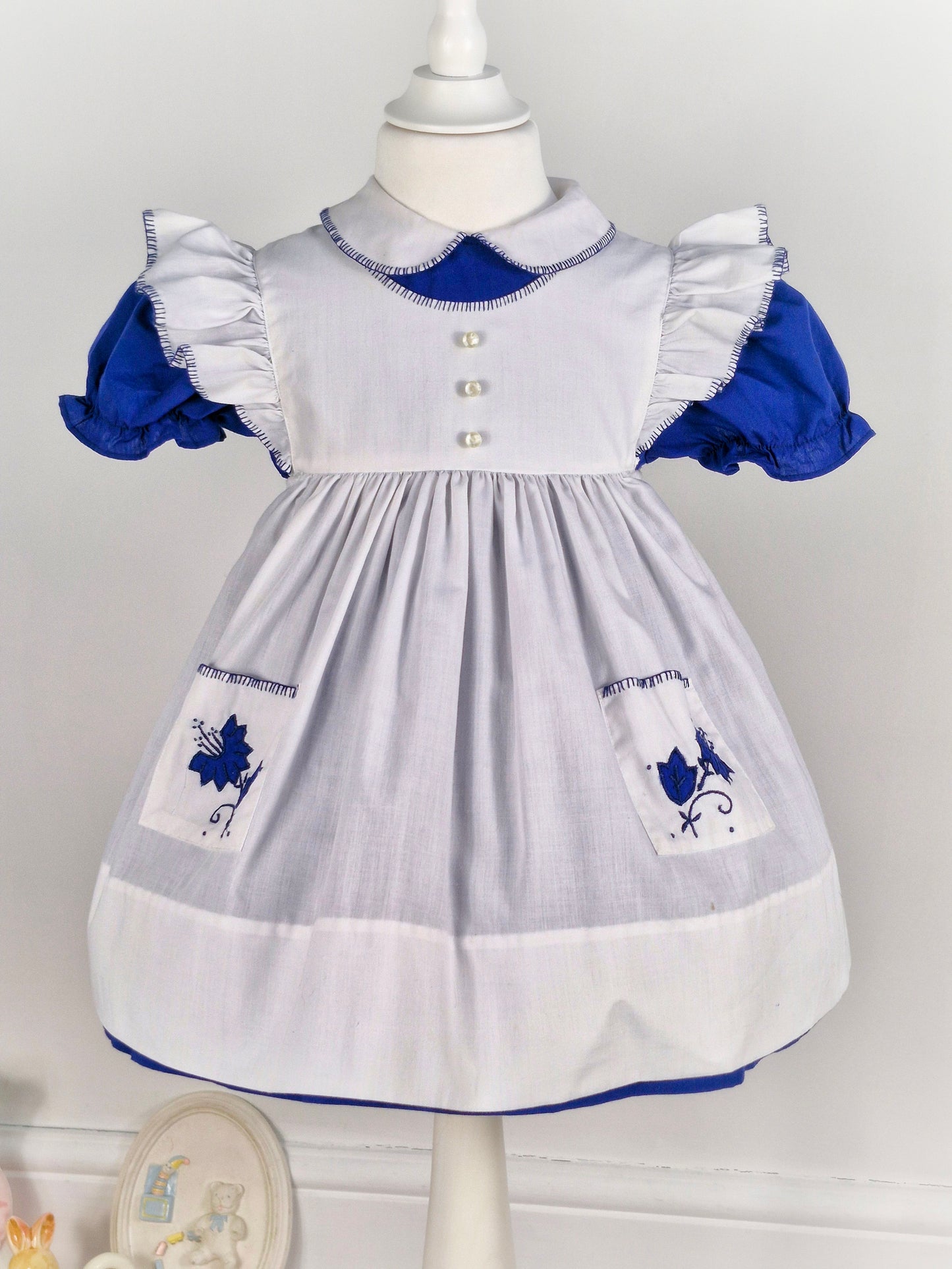 2-3 years. Vintage two-piece, navy dress with white collar and puff sleeves, with white flutter shoulder apron and embroidered pockets