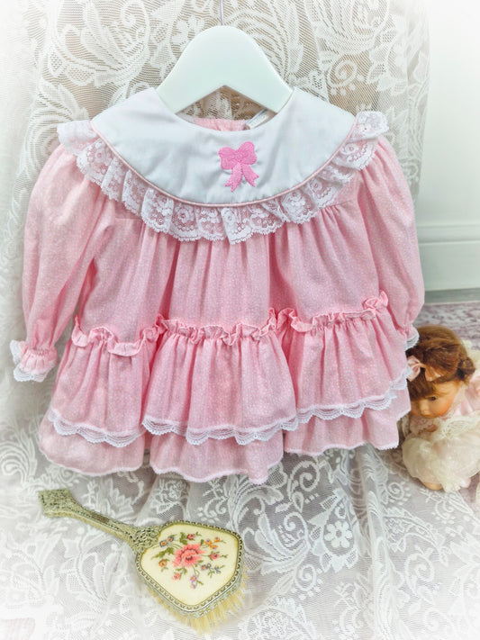 6-9 months. Pink, long sleeve, vintage Bryan with white bib and embroidered pink bow