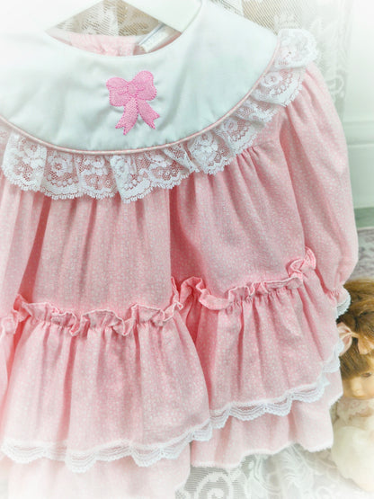 6-9 months. Pink, long sleeve, vintage Bryan with white bib and embroidered pink bow